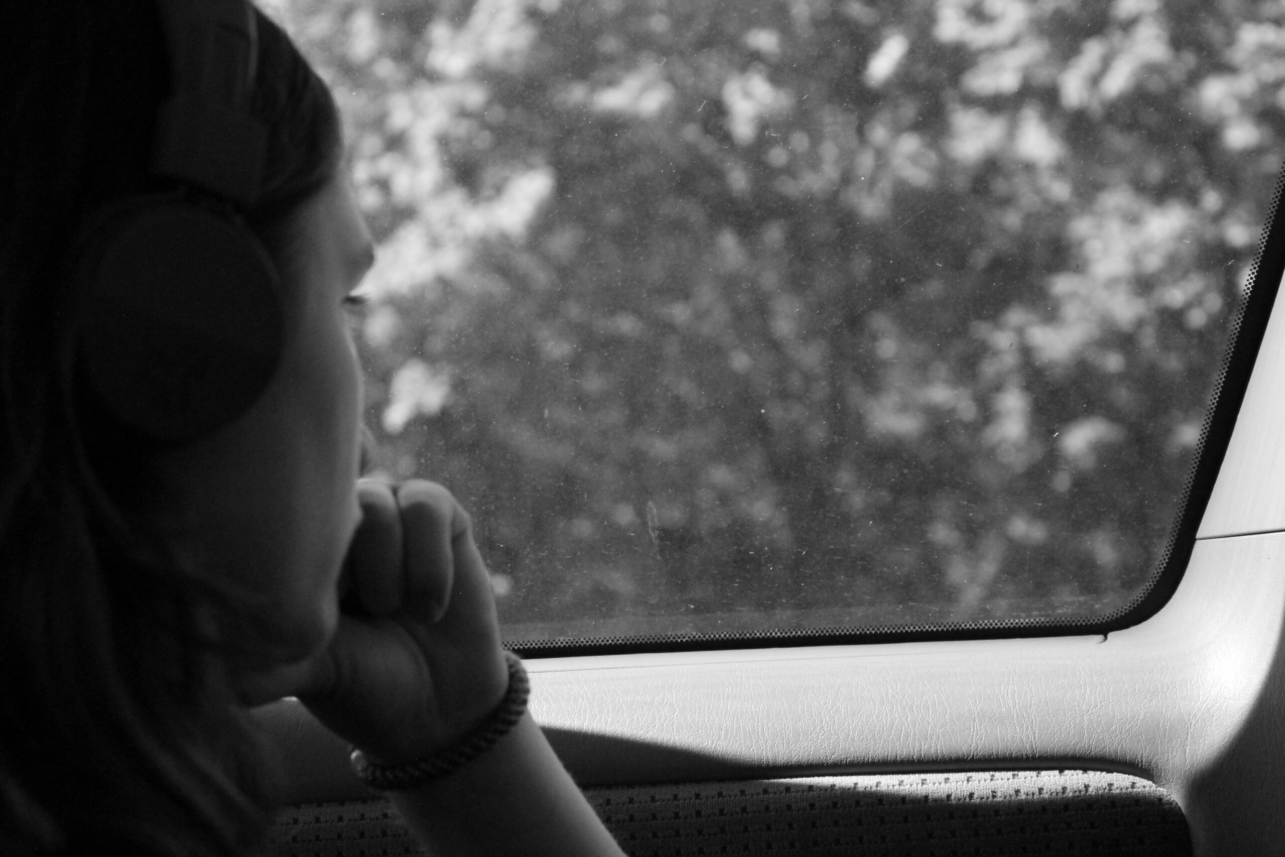 Grayscale Photo of a Woman in a Car Looking Outside the Window